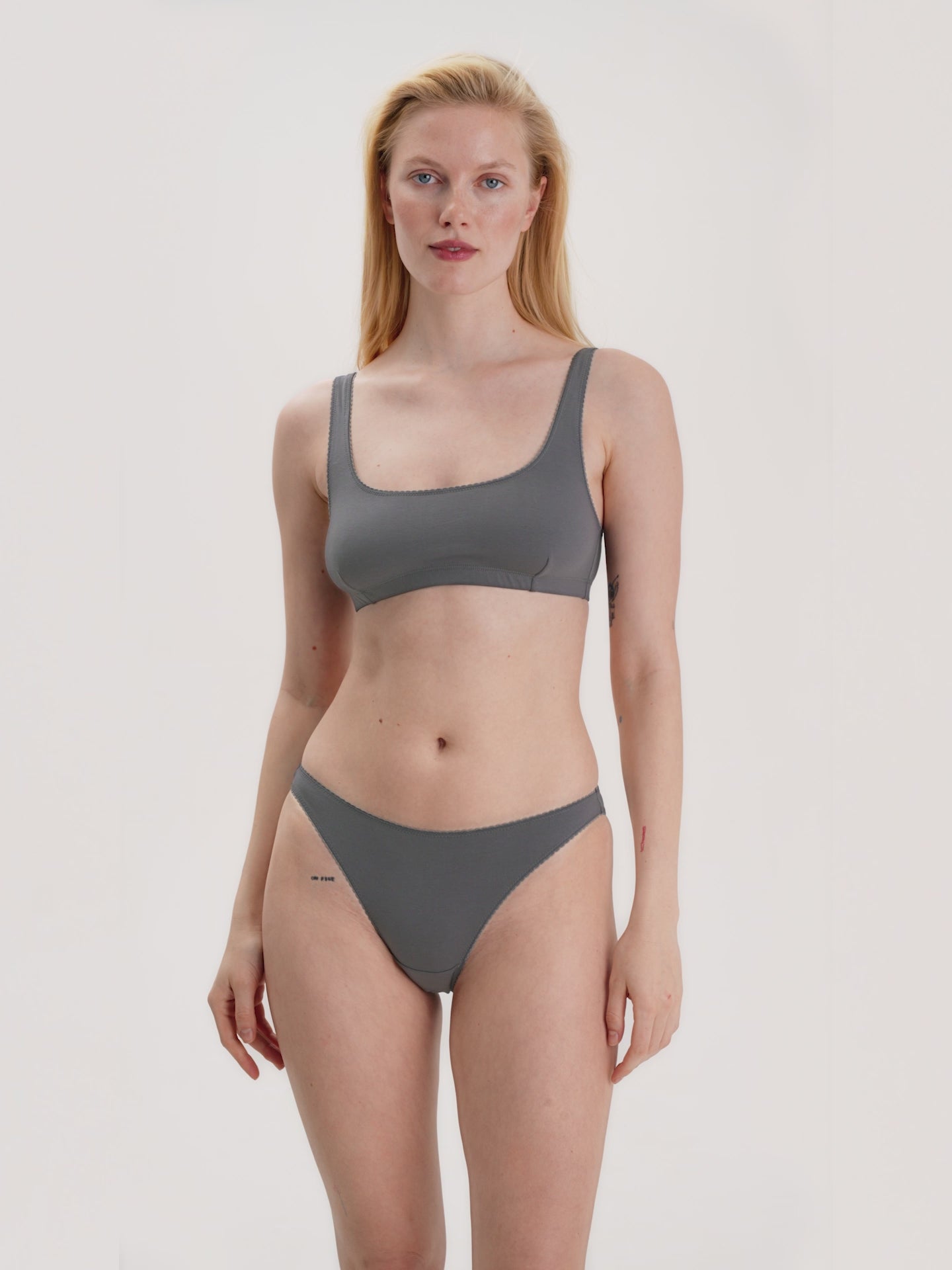 Woman wearing a gray top and bikini set on a plain background