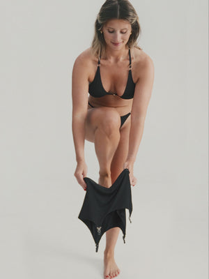 Woman wearing black lingerie set and putting on suspender belt with stockings