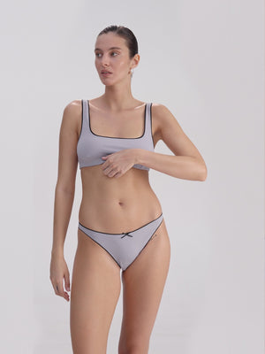 Woman wearing a lilac underwear set on a plain background