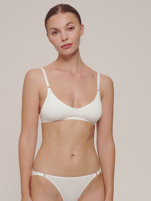 A woman wearing a white soft cup bra and bikini undies with metal rings.