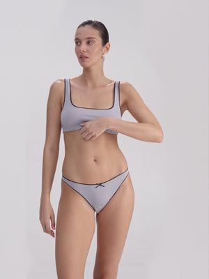Woman wearing a lilac underwear set on a plain background