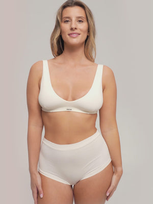 A woman wearing a warm ivory colored high waist brief and matching bra.