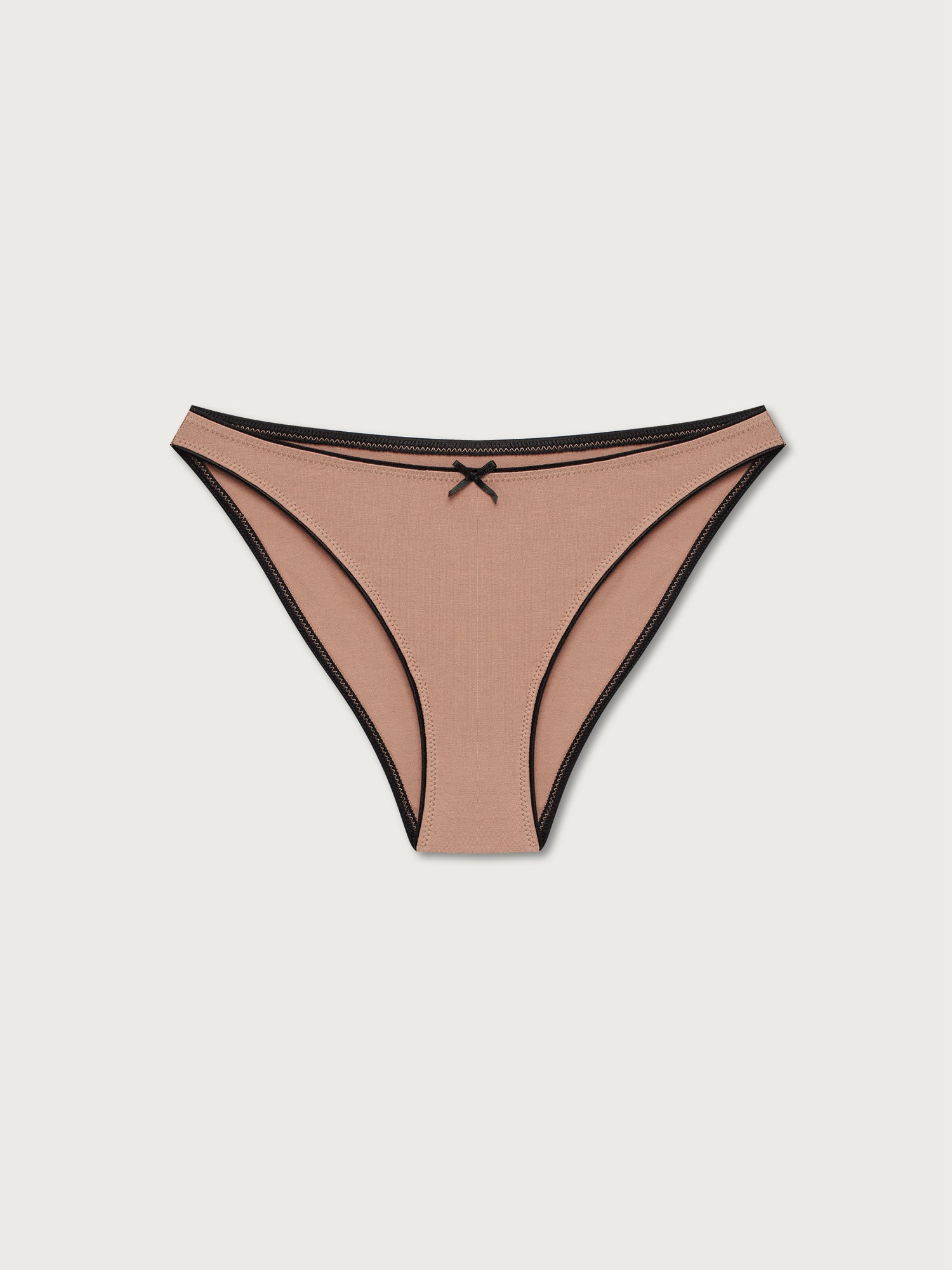 Beige bikini undies with black trim on a light gray background